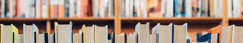 A shelf full of books of varying sizes and colours