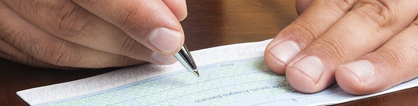 Close up of hands writing a cheque