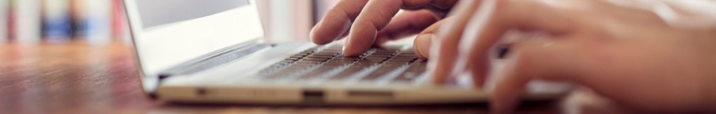 Hands typing on a laptop keyboard