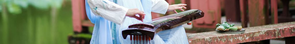 Woman in traditional Chinese dress playing a guqin