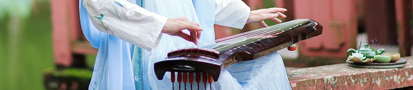 Woman in traditional Chinese dress playing a guqin