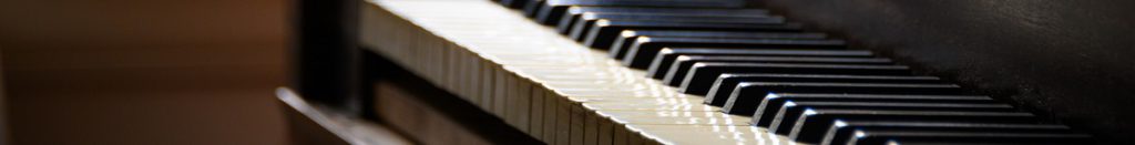 An antique piano sits by a rustic window